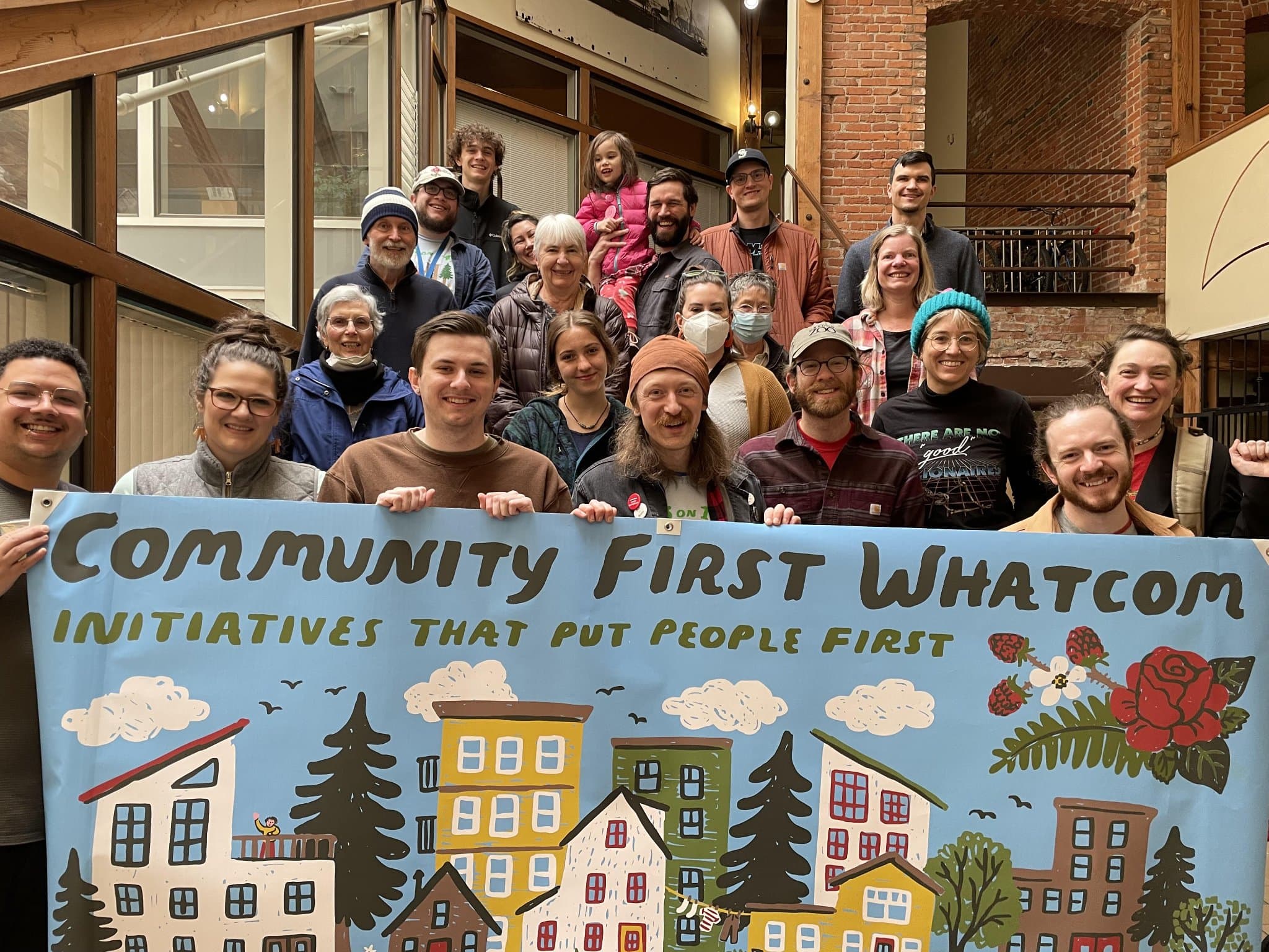 Community First Whatcom members with banner showing neighborhood illustration